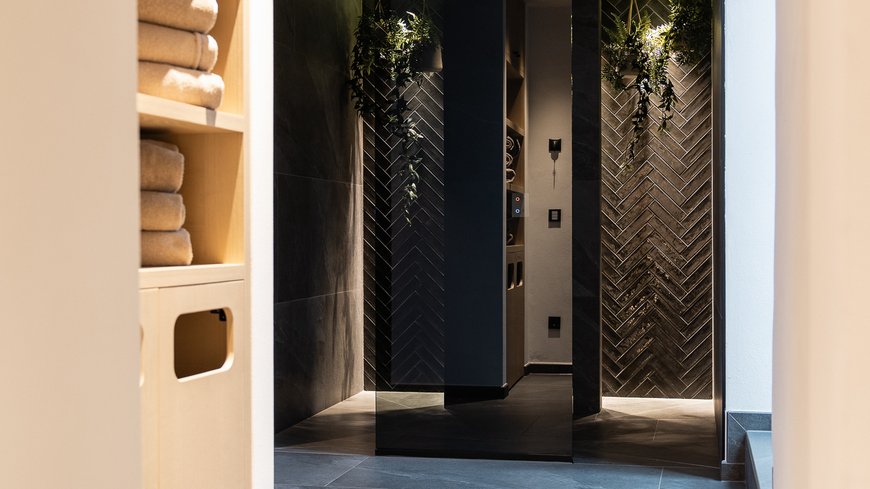 Benessere all’Aquila Nera Corridoio moderno con scaffali per asciugamani e piastrelle scure
