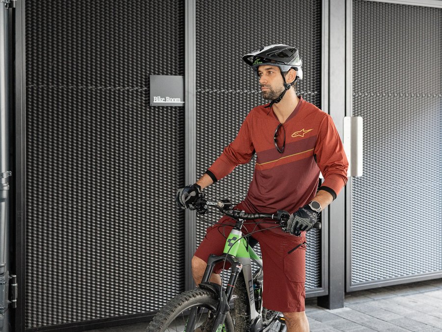 Discover the Schwarzer Adler Man with helmet standing with mountain bike in front of bike room entrance