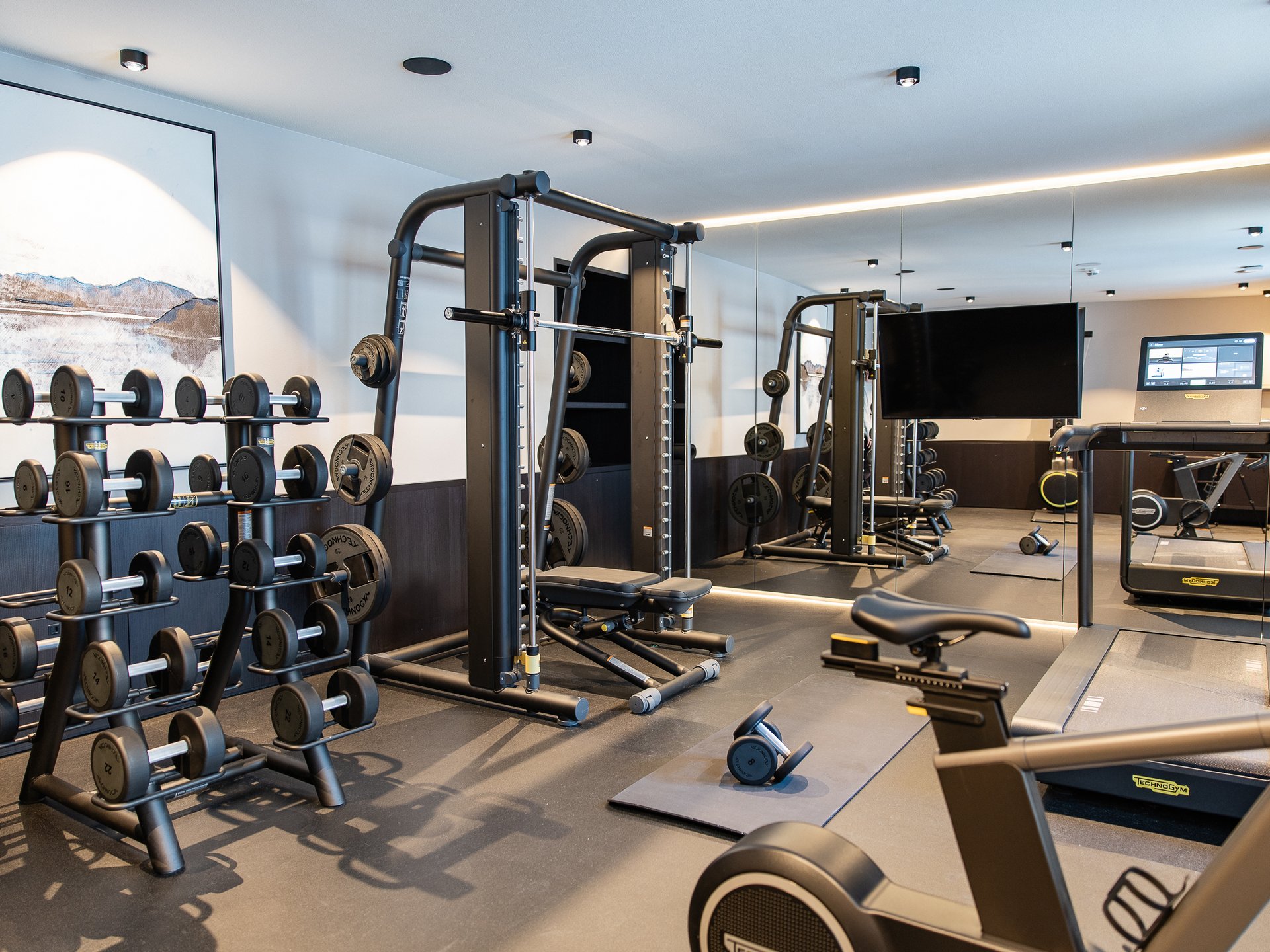 Modern gym with weights, exercise machines, and a mirrored wall
