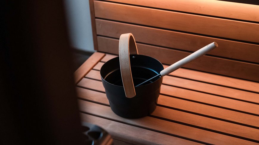Benessere all’Aquila Nera Secchio da sauna e mestolo su una panca di legno in sauna