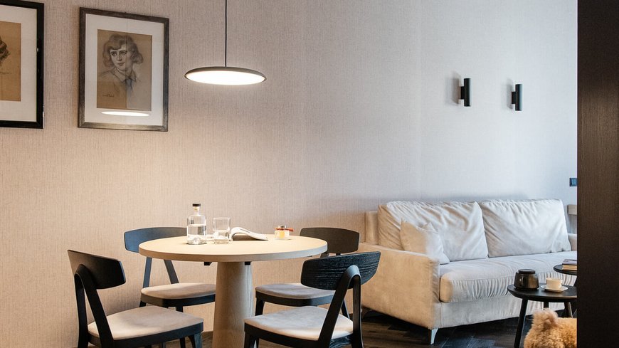 Modernes Wohnzimmer mit Tisch, Stühlen, Sofa und kleinem Hund auf Holzboden