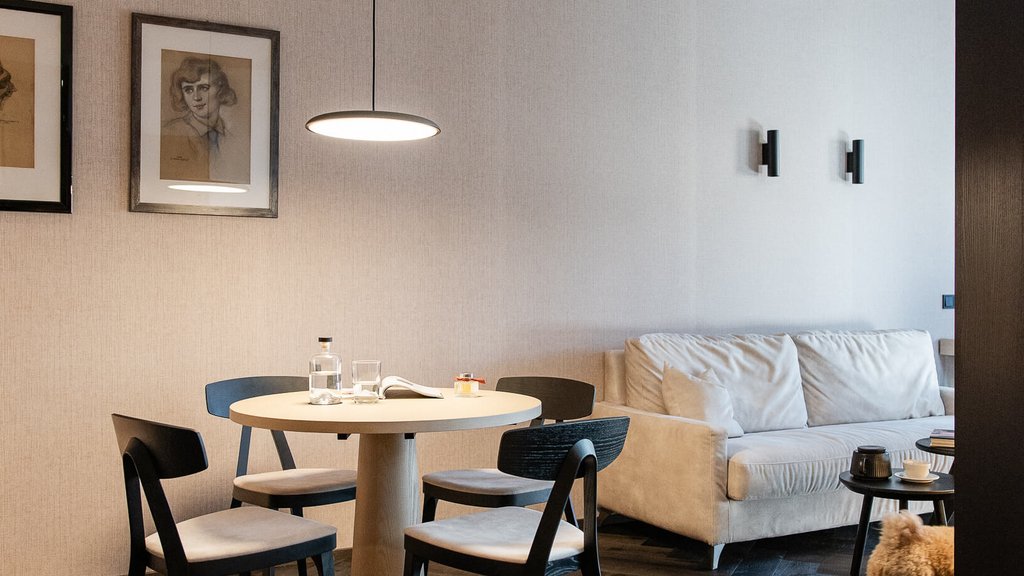 Modernes Wohnzimmer mit Tisch, Stühlen, Sofa und kleinem Hund auf Holzboden