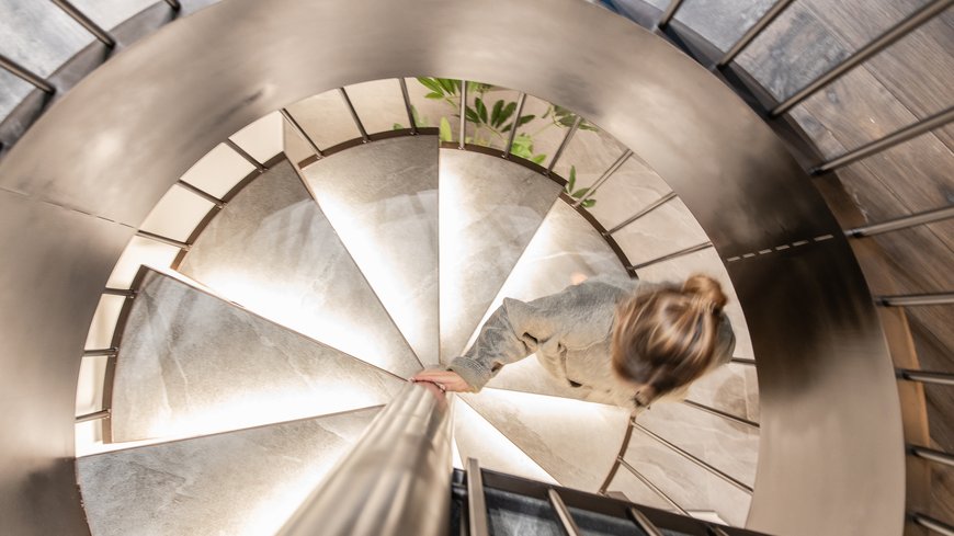 Frau steigt eine beleuchtete Wendeltreppe hinab