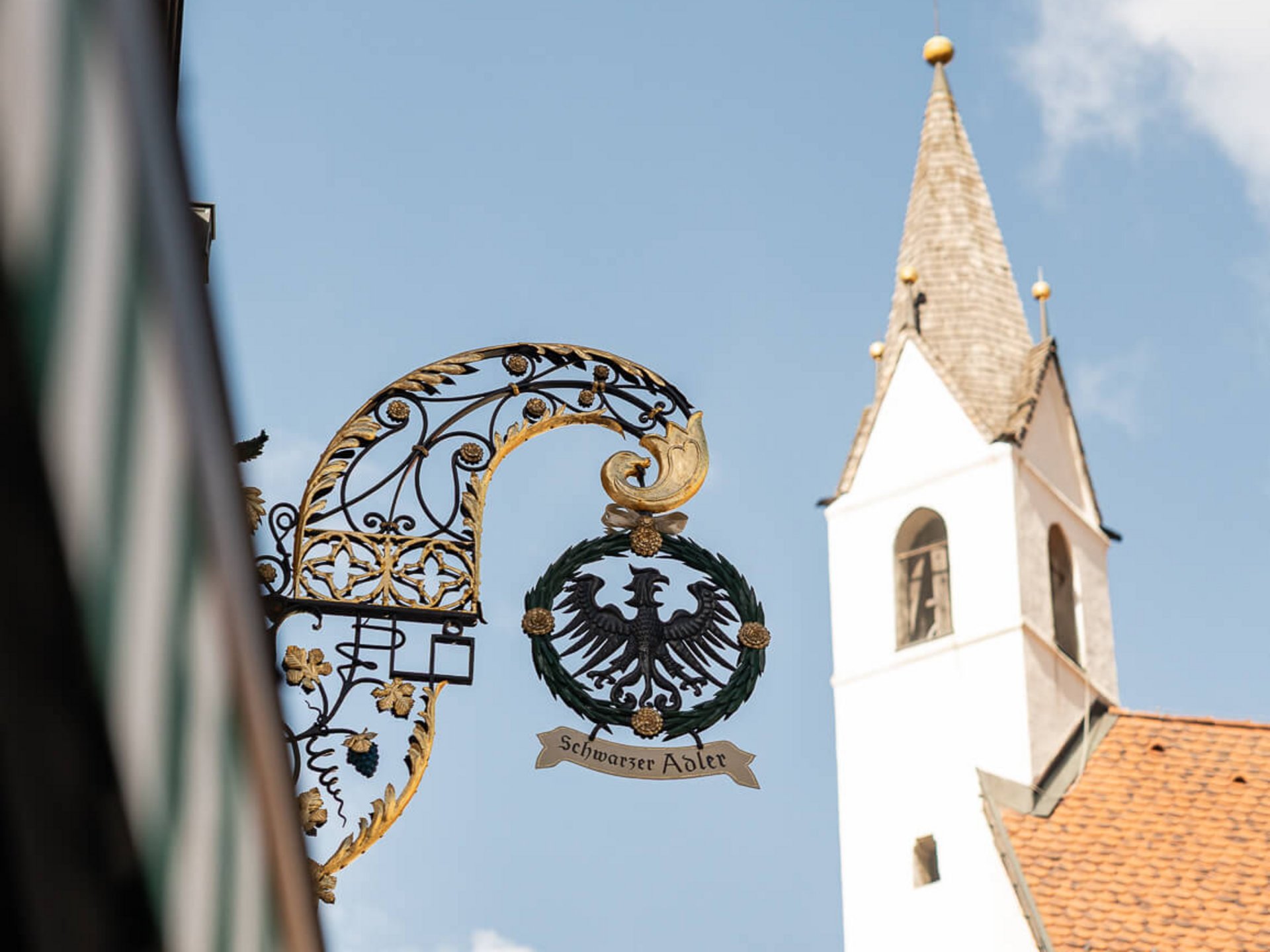 Insegna storica Aquila Nera davanti a chiesa sotto cielo azzurro