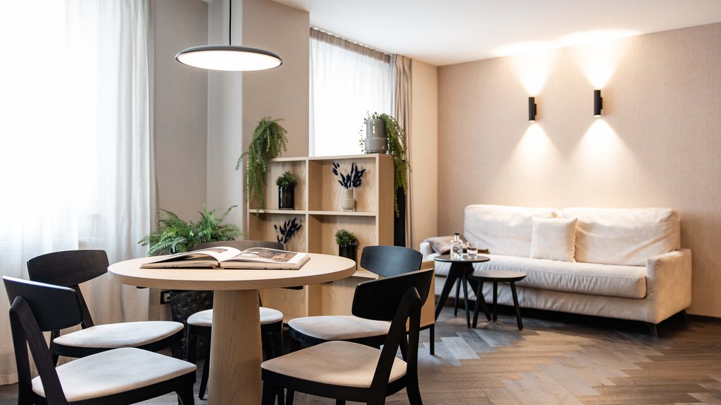 Modernes Wohnzimmer mit Esstisch, vier Stühlen, Sofa und Pflanzen