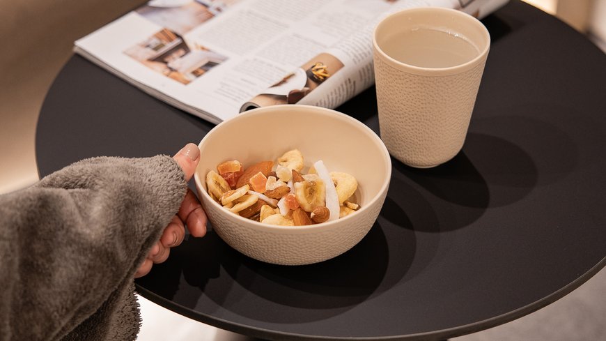 Benessere all’Aquila Nera Mano che prende ciotola con frutta secca, acqua e rivista su tavolo nero