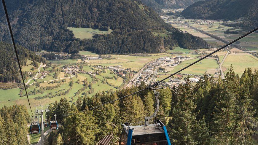 Cable car over forested mountain with valley and mountains in background