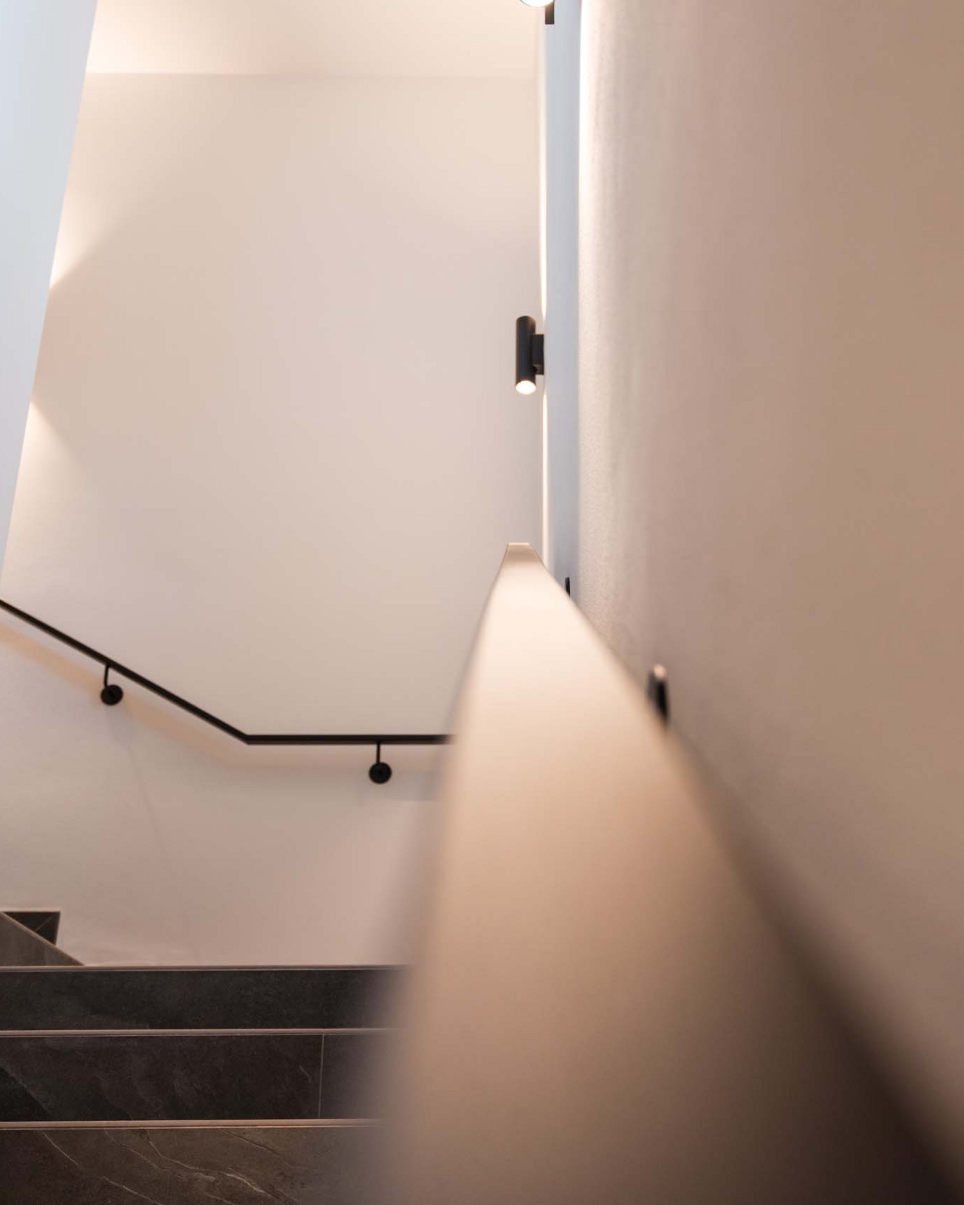 Minimalist staircase with dark steps and white handrail