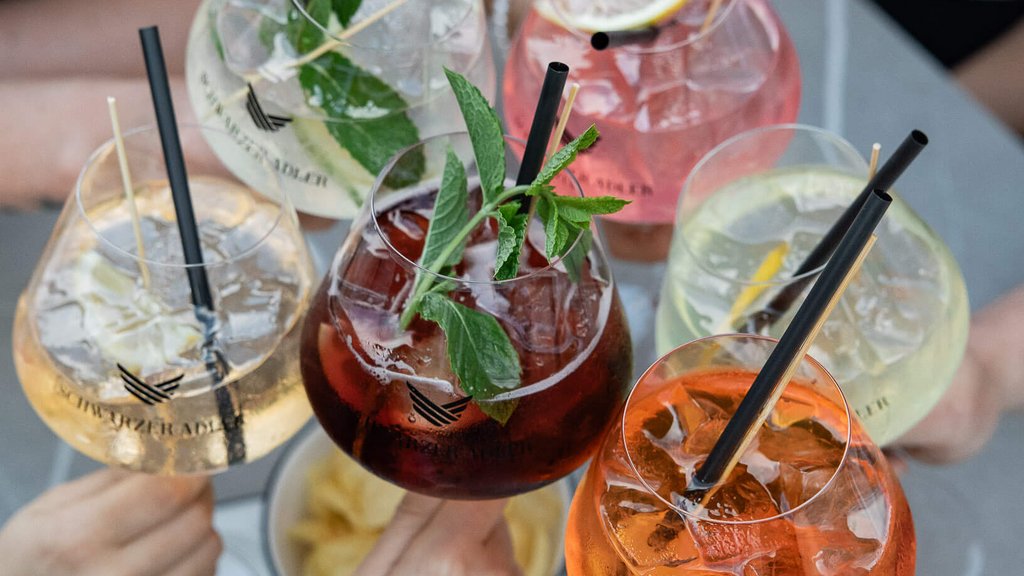 Five colorful cocktails held by people for a toast