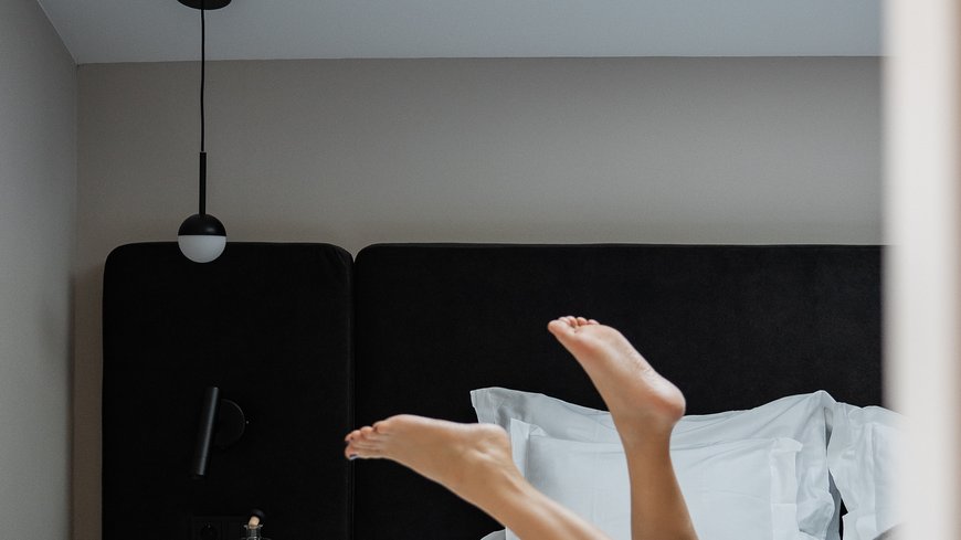 Feet of a person lying on a white bed in a modern bedroom