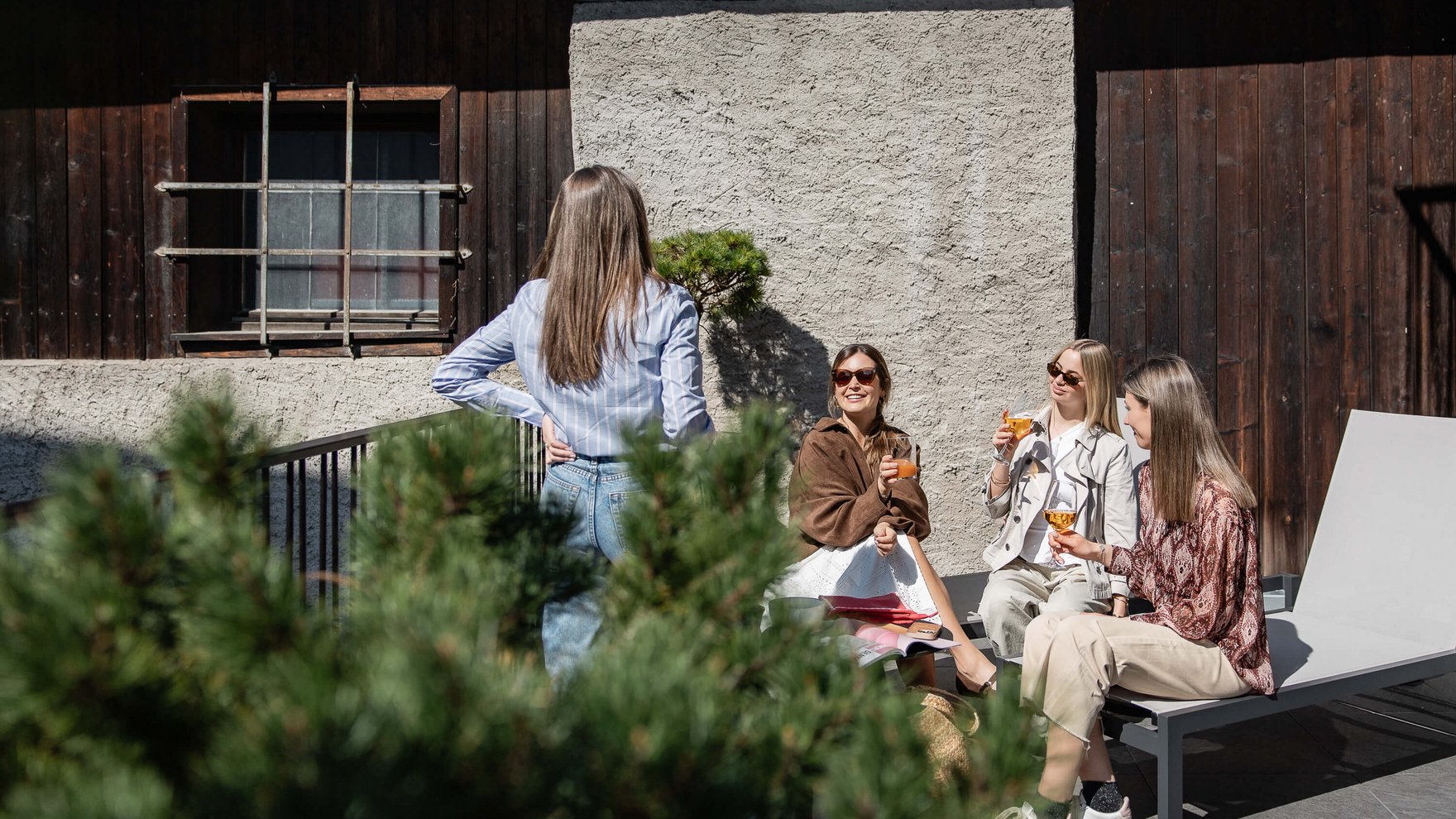 Quattro donne che bevono insieme bevande su una terrazza soleggiata