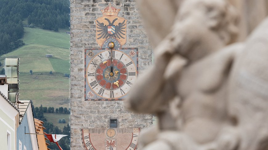 The laid-back town on the Isarco/Eisack river Historic clock tower with coat of arms in an alpine town