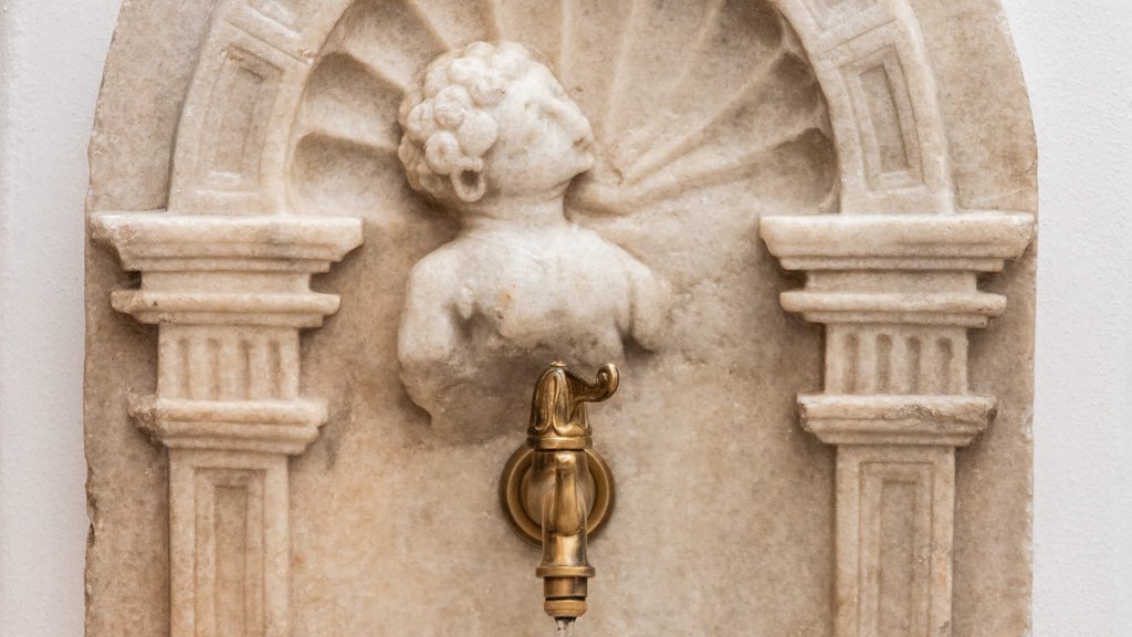 Antique water tap with marble cherub bust mounted on wall
