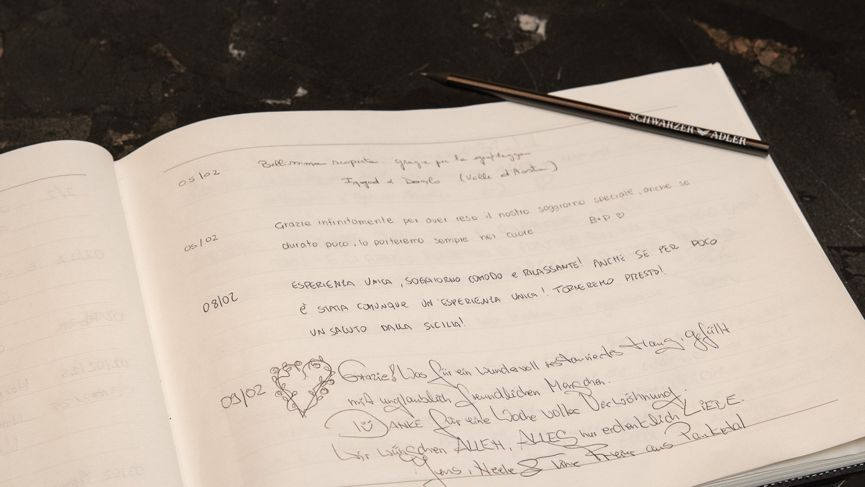 Discover the Schwarzer Adler Open guestbook with handwritten messages and pen on dark table