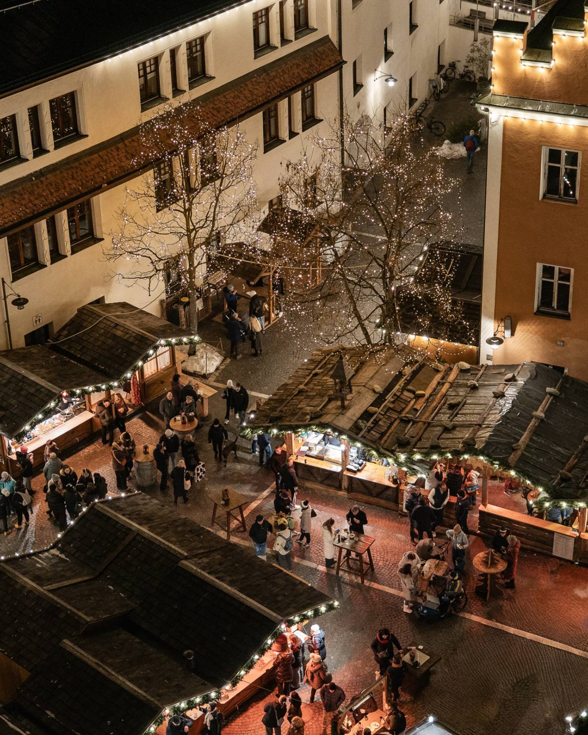 Weihnachtsmarkt bei Nacht mit Ständen und beleuchteten Gebäuden
