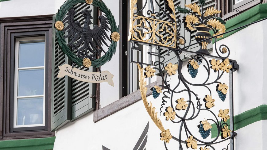 The laid-back town on the Isarco/Eisack river Schwarzer Adler restaurant sign with gold decorations on white building