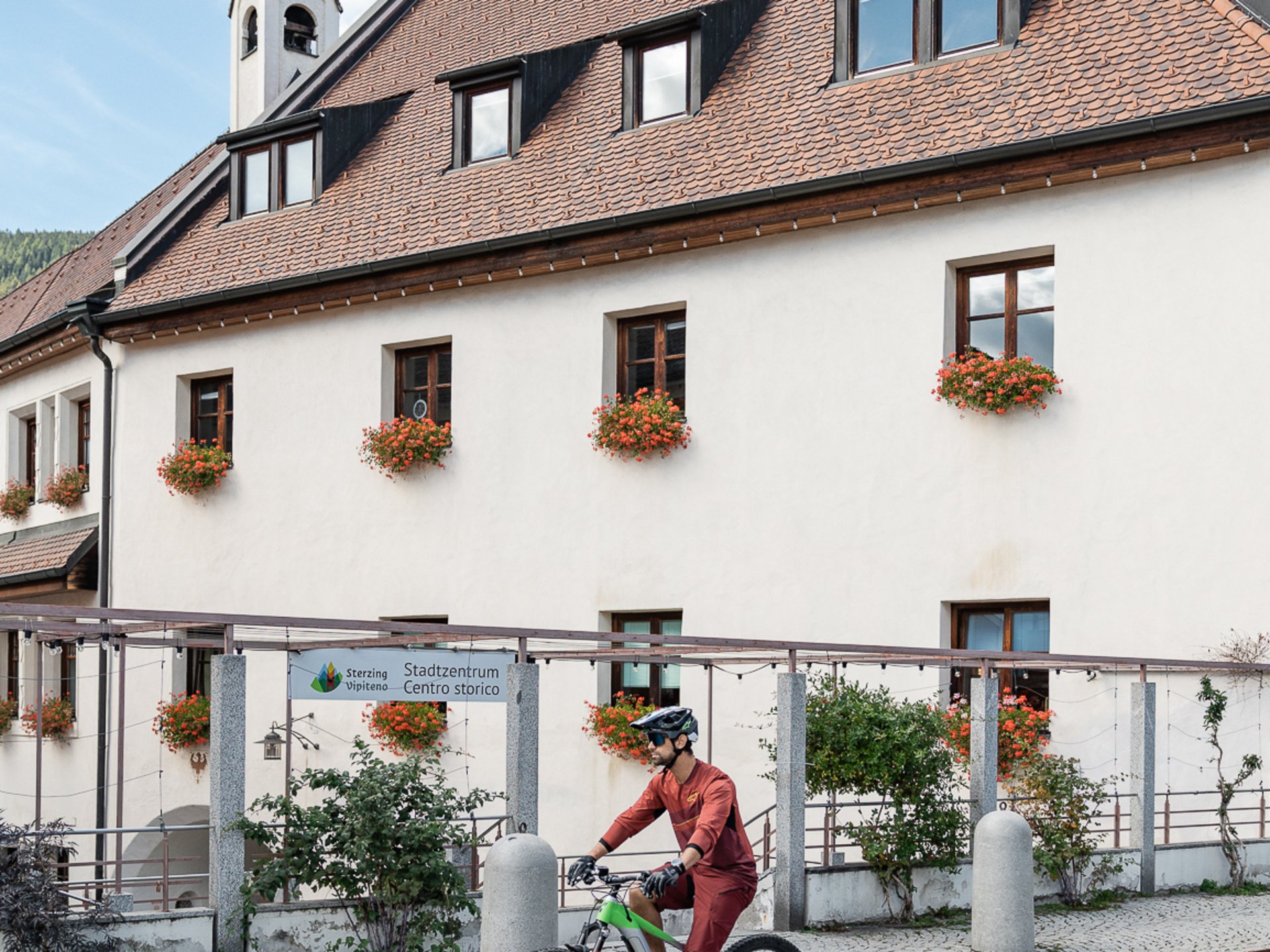 Cyclist in front of traditional building with flowers on windows in Sterzing.