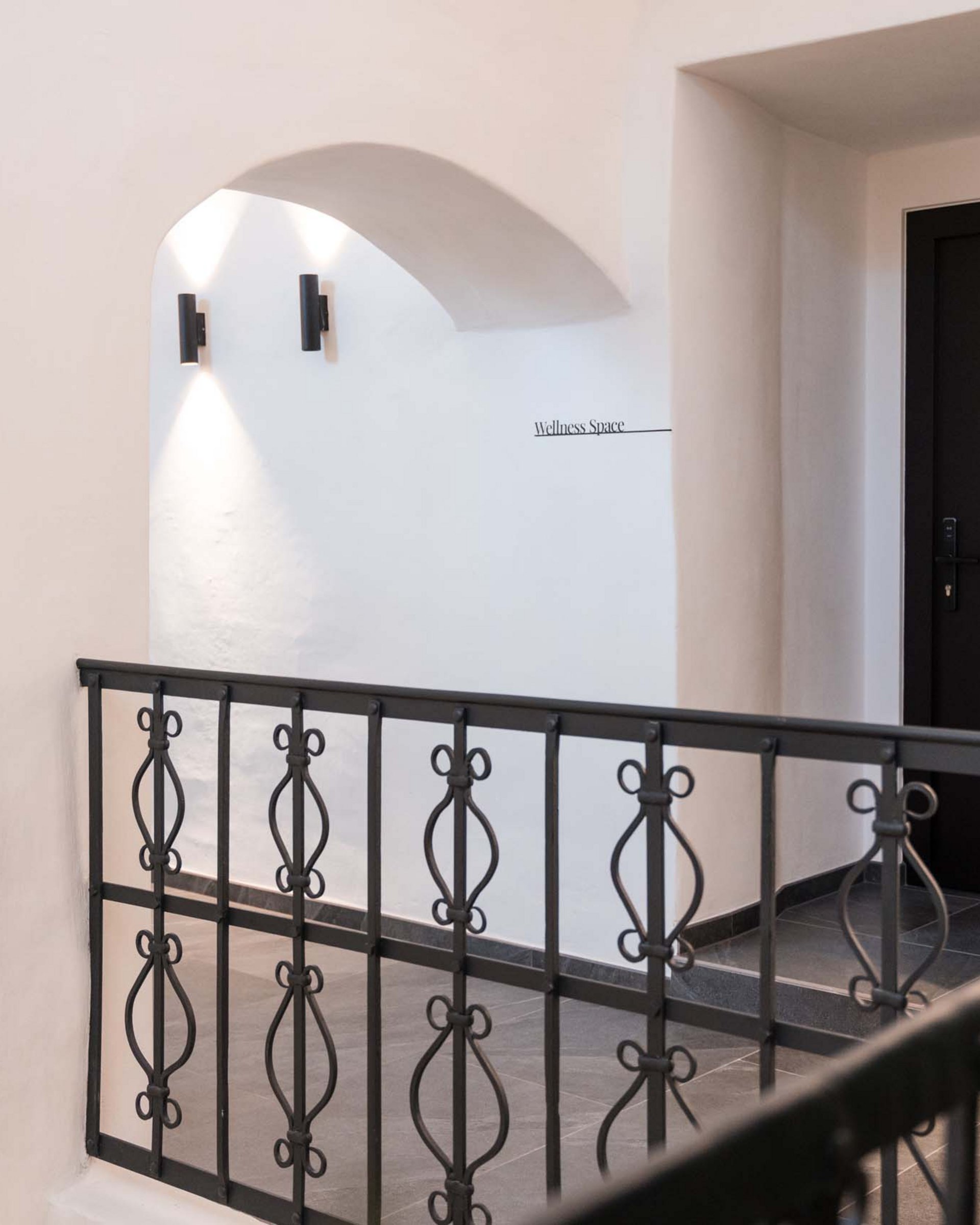 Bright hallway with black railing and door to wellness space