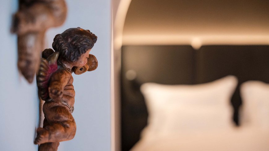 Holzengel an einer Wand neben einem unscharfen Bett im Hintergrund