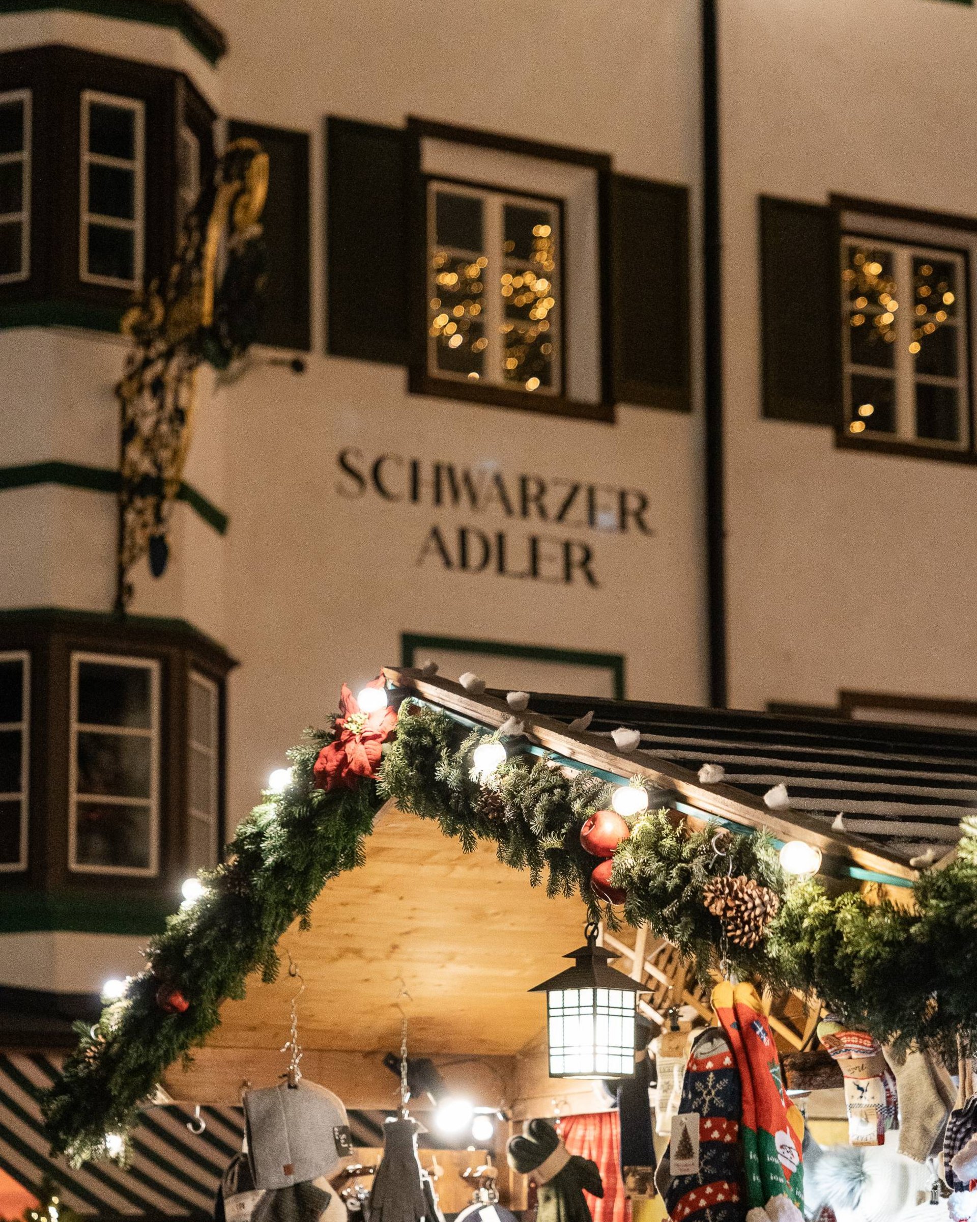 Weihnachtsmarktstand mit Mützen, Handschuhen und Dekoration beleuchtet