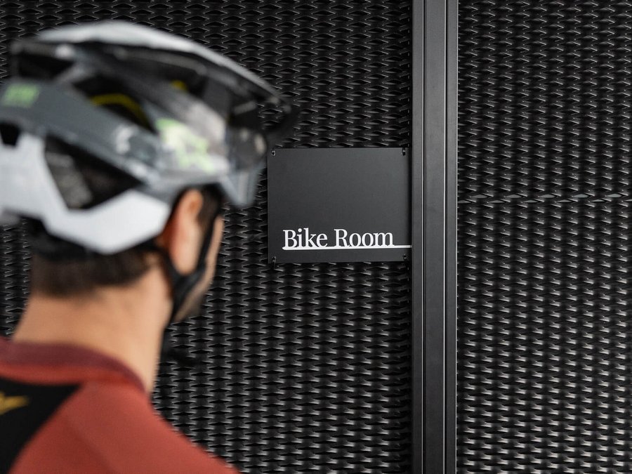 Cooles Rennradhotel in Südtirol Person mit Fahrradhelm vor einem Schild mit der Aufschrift Bike Room