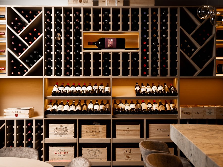 Discover the Schwarzer Adler Wine rack with many bottles and wooden boxes in a modern wine cellar