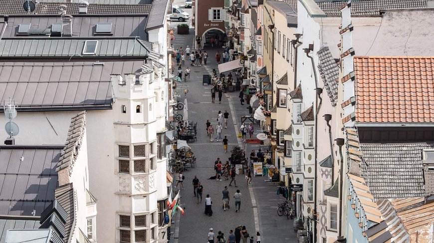 The laid-back town on the Isarco/Eisack river Busy pedestrian street with historic buildings and people in a European town