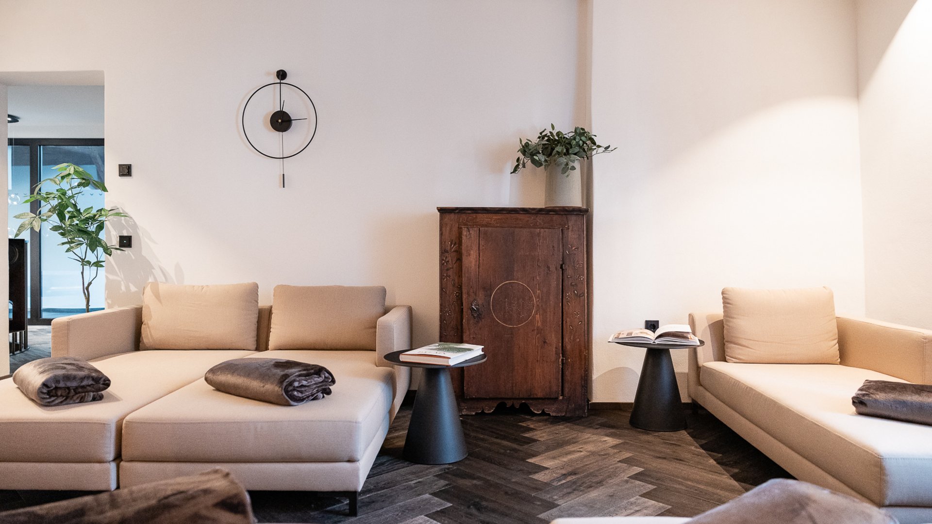 Modernes Wohnzimmer mit beigen Sofas, schwarzen Beistelltischen und Holzboden