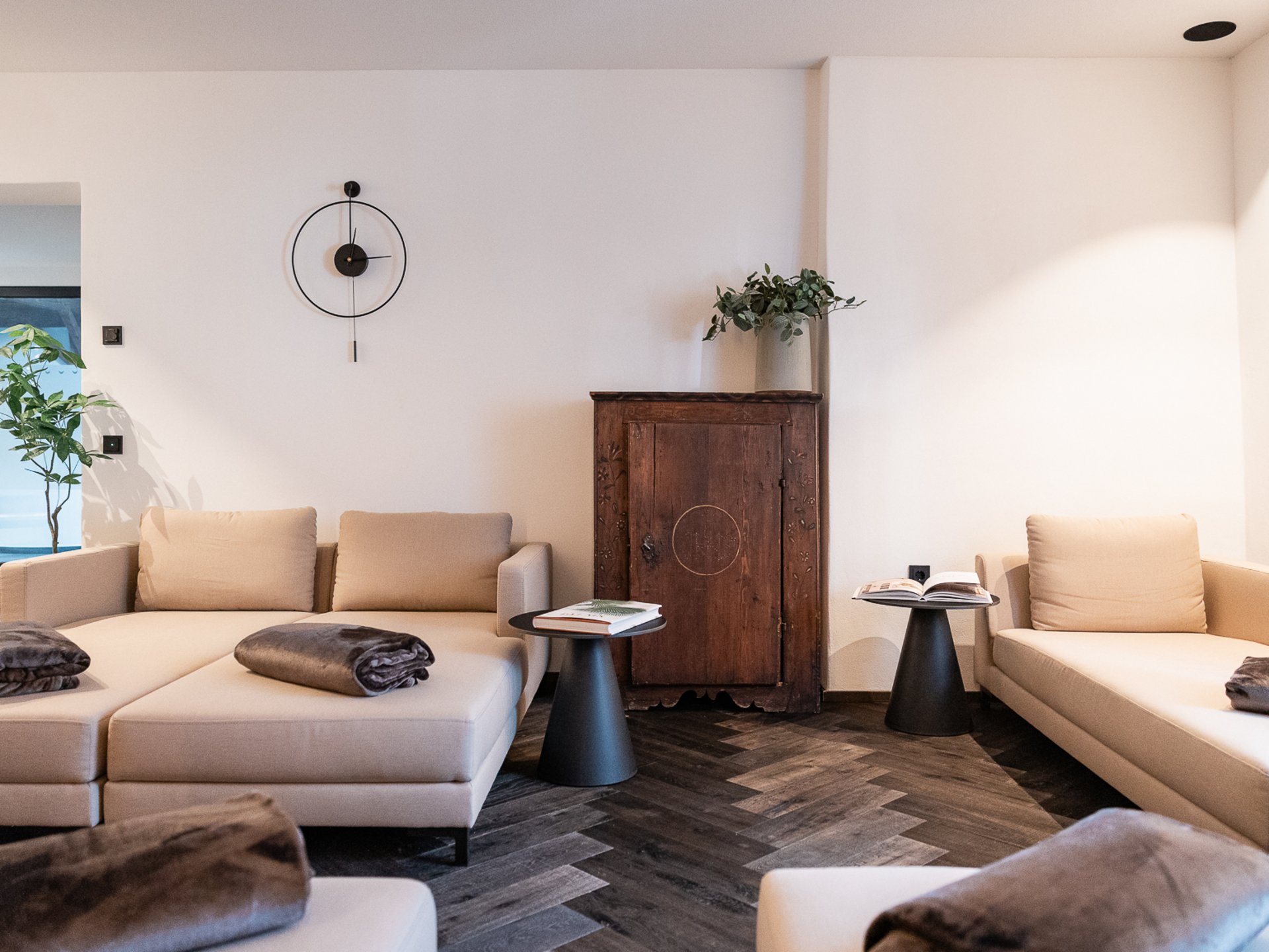 Modern living room with beige sofas, black side tables, and wooden flooring