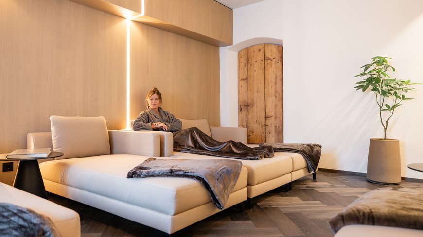 Frau entspannt auf beige Sofa in gemütlichem, modernem Wohnzimmer
